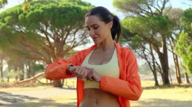 Bir spor kızı sabahın erken saatlerinde koşuyor. Atletik bluzlu ve taytlı bir kadın maratondan sonra kalori alımını artırıyor. Atletik kadın ormanda koşmadan önce nabzını kontrol ediyor.