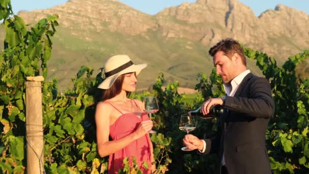 グラスに赤ワインを注ぐ豊かなカップルの試飲 ブドウ畑での個人的な卒業 新婚旅行中にイタリアのワイナリーでワインを飲むのが好きなカップル ブドウ畑でワインをテストする男女 — ストック動画