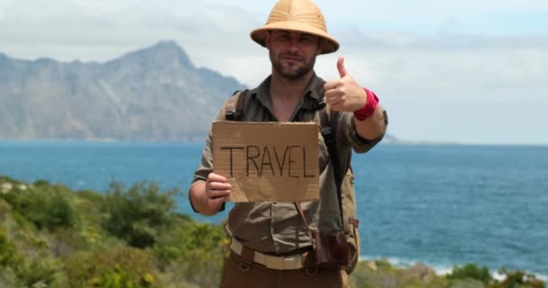 ビーチでリラックスした若い男旅行者 海を見てハンサムな自信のある男は 休日を楽しんでいます 太陽の帽子を被った旅人がカメラを見てこう言います 若い旅行者の肖像 — ストック動画