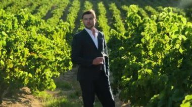 man in a white shirt with a glass of wine at a winery in france. Professional wine expert, sommelier holding glass of wine, tasting, rating and reviewing. Man testing wine in a factory or warehouse