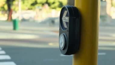 Womans hand pushing a yellow downtown city street crosswalk button. pedestrian crossing call button. Hand pushing button to cross. Intersection button pressed to initiate the crosswalk signal.