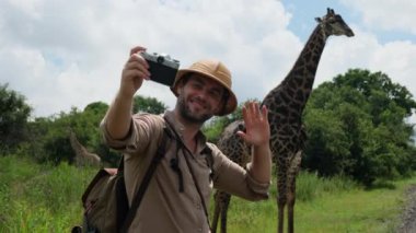 A lone giraffe in the wild of the African savannah walks past a safari car and tourists. a tourist in safari clothes takes a photo of a giraffe in africas national park among the jungle