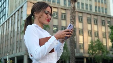 Smiling woman wearing formal suit using mobile phone typing text messages. Closeup business woman typing message on mobile phone. Hand of woman using texting mobile phone or chat.