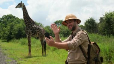 Giraffe Giraffa camelopardalis in Kruger National Park, South Africa.a male traveler in a safari hat takes a selfie against the background of a giraffe in the savannah