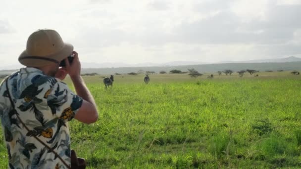 アフリカのサバンナの野生のゼブラは サファリカーや観光客を通ります サファリの服を着た観光客がジャングルの中のアフリカ国立公園のゼブラの写真を撮ります — ストック動画