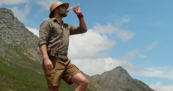 徒步旅行时 背着背包的男性游客喝着新鲜的山水 经过长途旅行到达山顶后 人们在山顶上喝水 背着背包从瓶子里喝水的旅行者 — 图库视频影像