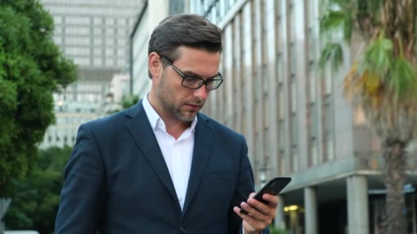 携帯電話の入力テキストメッセージを使用して正式なスーツを着て笑顔男 電話でビジネスマンのメッセージを入力して閉じます 携帯電話やチャットを使用して男の手 — ストック動画