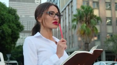 Yetişkin bir gencin portresi başarılı bir Amerikalı iş kadını, sekreter, satış müdürü, iş danışmanı, resmi gömlekli. Beyaz gömlekli bir iş kadını telefonundaki hisse senedi fiyatlarını kontrol ediyor.