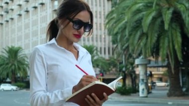 Yetişkin bir gencin portresi başarılı bir Amerikalı iş kadını, sekreter, satış müdürü, iş danışmanı, resmi gömlekli. Beyaz gömlekli bir iş kadını telefonundaki hisse senedi fiyatlarını kontrol ediyor.