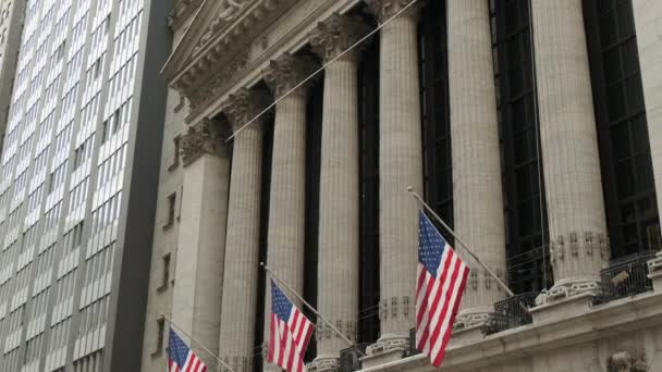 有名なウォール街とニューヨーク 愛国者の旗とニューヨーク証券取引所の建物 ニューヨーク証券取引所の角にあるウォール街の道路標識 ニューヨーク証券取引所 — ストック動画