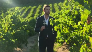 Takım elbiseli karizmatik bir adam şaraphanede beyaz şarap içiyor. Şarap kadehi tutan gülümseyen genç adam. Resmi kıyafetli, şarap içen olgun bir adamın portresi..