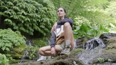 Seyahat ve özgürlük. Kadın tropikal şelale manzarasından hoşlanıyor. Endonezya, Bali 'de şelale ve kadın gezgin. Kollarını kaldırarak gururla duran bir kız. Büyük şelale duvarının önünde..