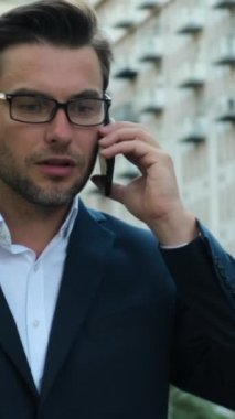Mutlu modern iş adamı şehirde akıllı telefondan konuşuyor. Gülümseyen profesyonel iş adamı takım elbiseli girişimci elinde telefonla şirket görüşmeleri yapıyor..
