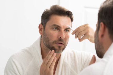 Banyoda sakalını kesen makaslı çıplak bir adam. Sakallı adam, sakallı erkek. Berber makası, berber dükkanı. Klasik berber dükkanı, sakalını kesen bir adam..