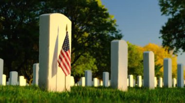 Sunset 'te Amerikan bayrakları. Mezarlıktaki anma günü anısına mezar taşlarında bayraklar var. Ulusal Mezarlıkta küçük Amerikan bayrakları ve mezar taşları Anma Günü sergisi.