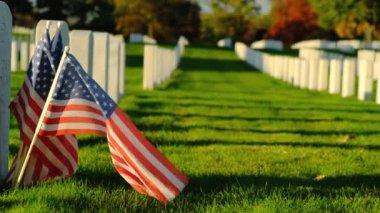 Sunset 'te Amerikan bayrakları. Mezarlıktaki anma günü anısına mezar taşlarında bayraklar var. Ulusal Mezarlıkta küçük Amerikan bayrakları ve mezar taşları Anma Günü sergisi.