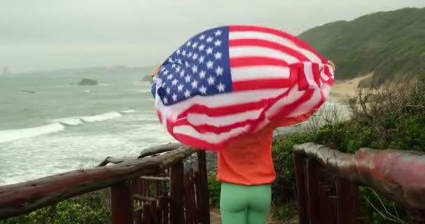 Девушка Туристка Ветровке Американским Флагом Стоящим Утесе Калифорнии Рядом Океаном — стоковое видео
