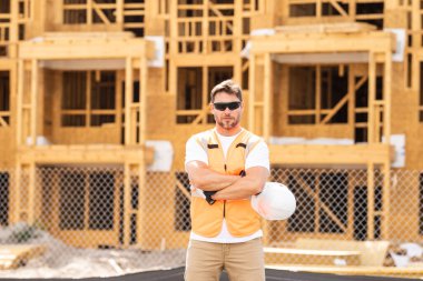 İnşaat alanındaki çatı ustası, Rıhtım inşaatında çalışıyor. Kameraya gülümseyen kasklı yakışıklı, genç bir müteahhit. Görevli inşaat işçisi. Müteahhit ve Tahta Ev Çerçevesi