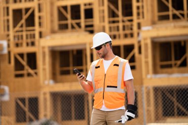 İnşaat alanındaki çatı ustası, Rıhtım inşaatında çalışıyor. Kameraya gülümseyen kasklı yakışıklı, genç bir müteahhit. Görevli inşaat işçisi. Müteahhit ve Tahta Ev Çerçevesi