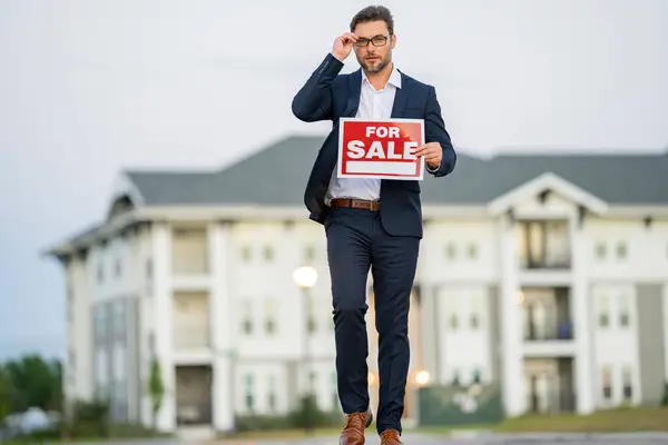 Buying and choosing housing. real estate agent in a suit holding a sign for rent or lease. Real estate agent holding pen pointing at contract document for client to sign home purchase agreement