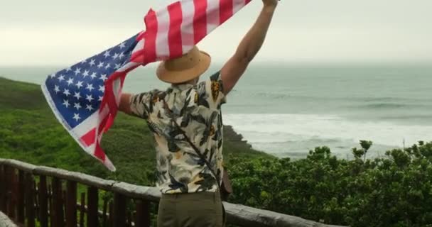 여행자는 국기를 자랑스럽게 있습니다 하이커 남자는 캘리포니아 해변에서 기념일 국기를 — 비디오