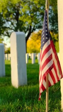 Ulusal Mezarlıkta gün batımında Amerikan bayrağı taşıyan mezarlar. Bilinmeyen asker mezarı. Gazi mezarlığı ve Amerikan bayrağı. Askeri Takdir Tatili Konsepti dikey