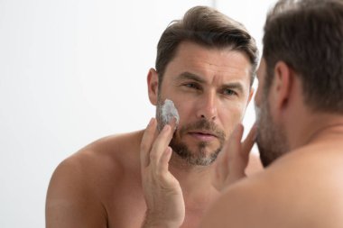 Bir adam aynanın önünde yüzüne losyon sürüyordu. Kişisel bakım ve kişisel bakım kavramı