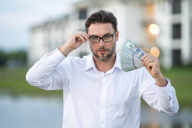 Attractive man is holding cash money in one hand. Joyful man with banknotes of money in his hands. Big financial luck and success, profit and cash. Rich man hands holding cash money clipart