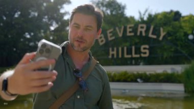 Havalı erkek turist Beverly Hills Amerika yakınlarında telefonuyla selfie çekiyor. Seyahat eden bir adam, cep telefonlu bir adam Los Angeles 'ta selfie çekiyor..