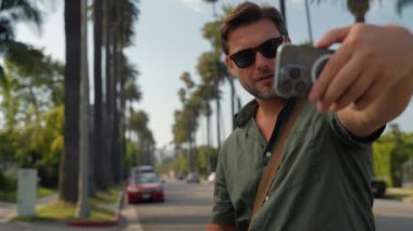 Havalı erkek turist Beverly Hills Amerika yakınlarında telefonuyla selfie çekiyor. Los Angeles 'ta cep telefonlu bir adam selfie çekiyor. Los Angeles 'ta selfie çeken bir turist.