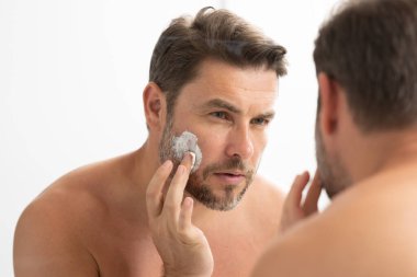 Bir adam aynanın önünde yüzüne losyon sürüyordu. Kişisel bakım ve kişisel bakım kavramı