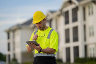 Yüksek görünüm donanımlı bir inşaat işçisi tozlu bir şantiyede güvenlik ve profesyonelliği vurguluyor