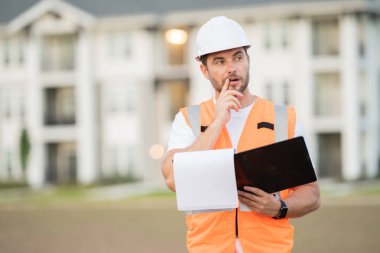 İnşaat işçisi, Afro-Amerikan bir adam, kasketli ve gülümsüyor. Mutlu müteahhit ya da müteahhit, ağır makineler. Binanın tepesinde inşaat işçisi. Üniformalı müteahhit
