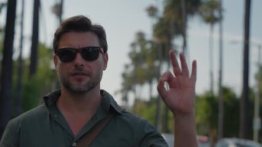 Beverly Hills, Hollywood, Los Angeles 'ta işler tıkırında. Yakışıklı beyaz adam sembol çiziyor, başparmağını kaldırıyor, iyi bir arkadaş fikrini onaylıyor. Mutlu komik adam göz kırpıyor ve tamam işareti gösteriyor.