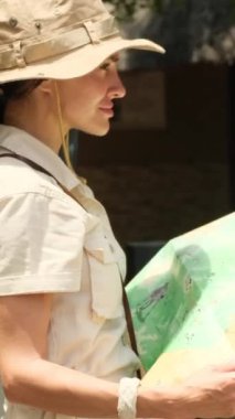 woman traveler with backpack looking to map. Holiday, journey, trip and summer summer travel concept. traveler stands near the safari car and looks at the route through the savannah on a paper map
