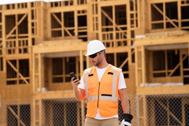 İnşaat alanındaki çatı ustası, Rıhtım inşaatında çalışıyor. Kameraya gülümseyen kasklı yakışıklı, genç bir müteahhit. Görevli inşaat işçisi. Müteahhit ve Tahta Ev Çerçevesi