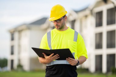 İnşaat işçisi, Afro-Amerikan bir adam, kasketli ve gülümsüyor. Mutlu müteahhit ya da müteahhit, ağır makineler. Binanın tepesinde inşaat işçisi. Üniformalı müteahhit