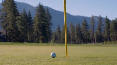 Yeşil sahadaki beyaz golf topu fotokopi uzayı ile aydınlık bir günde bulanık golf sahasında çekilecek. Spor, eğlence sektörü. Golf topu ve golf sopası yeşil çimlerin üzerinde.