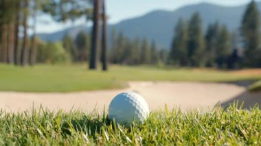 Yeşil sahadaki beyaz golf topu fotokopi uzayı ile aydınlık bir günde bulanık golf sahasında çekilecek. Spor, eğlence sektörü. Golf topu ve golf sopası yeşil çimlerin üzerinde.