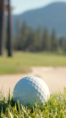 Yeşil sahadaki beyaz golf topu fotokopi uzayı ile aydınlık bir günde bulanık golf sahasında çekilecek. Spor, eğlence sektörü. Golf topu ve golf sopası yeşil çimlerin üzerinde.
