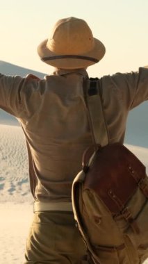 Merzouga Fas çölünde yürüyen bir adam. Sahara 'da sabah ışığı. Kumullar ve çizgiler, manzara manzarası. Kuzey Afrika. Yalnız adam çölde duruyor, ayak izleri, güneşli bir gün. Adam altın gün batımını izliyor