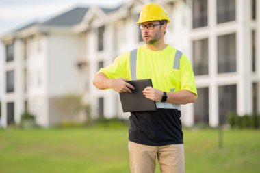 İnşaat işçisi, Afro-Amerikan bir adam, kasketli ve gülümsüyor. Mutlu müteahhit ya da müteahhit, ağır makineler. Binanın tepesinde inşaat işçisi. Üniformalı müteahhit
