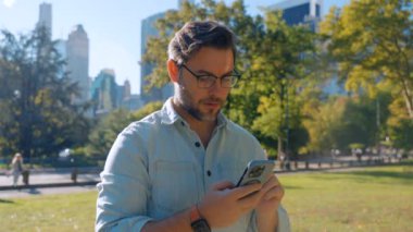 Central Park 'taki New York City' de telefonundan iyi haberleri okuyan bir adam. Heyecanlı mutlu adam piyango oyunu oynayarak, bahis oynayarak, mobil uygulama mesajında hediye alarak mutlu oluyor.