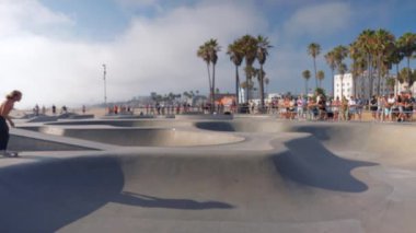Adamın biri Los Angeles 'taki Venice plajında lunapark treninde kayıyor. Parkta paten kayarken el ele tutuşan heyecanlı kadınlar. Plajda palmiye ağaçlarıyla paten kayıyor.