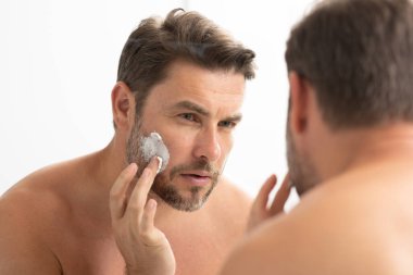 Bir adam aynanın önünde yüzüne losyon sürüyordu. Kişisel bakım ve kişisel bakım kavramı