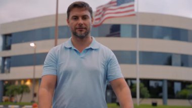 Amerikan bayrağı. Rüzgarda dalgalanan Amerikan bayrağı. Gömlekli adam, ellerini Amerikan bayrağının arka planına dayayarak kalp yapıyor. Mutlu vatansever adam Amerika 'ya olan sevgisiyle bir kalp yapar.