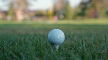 Yeşil sahadaki beyaz golf topu fotokopi uzayı ile aydınlık bir günde bulanık golf sahasında çekilecek. Spor, eğlence sektörü. Golf topu ve golf sopası yeşil çimlerin üzerinde.