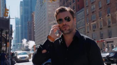 New York 'ta 5. Cadde' de tişörtlü bir iş adamı cep telefonuyla konuşuyor. İş yerinde konuşan yakışıklı bir adam. Meşgul profesyonel yönetici New York 'ta cep telefonu caddesinde arama yapıyor.