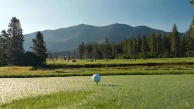 Yeşil sahadaki beyaz golf topu fotokopi uzayı ile aydınlık bir günde bulanık golf sahasında çekilecek. Spor, eğlence sektörü. Golf topu ve golf sopası yeşil çimlerin üzerinde.