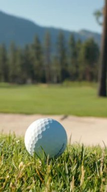 Yeşil sahadaki beyaz golf topu fotokopi uzayı ile aydınlık bir günde bulanık golf sahasında çekilecek. Spor, eğlence sektörü. Golf topu ve golf sopası yeşil çimlerin üzerinde.